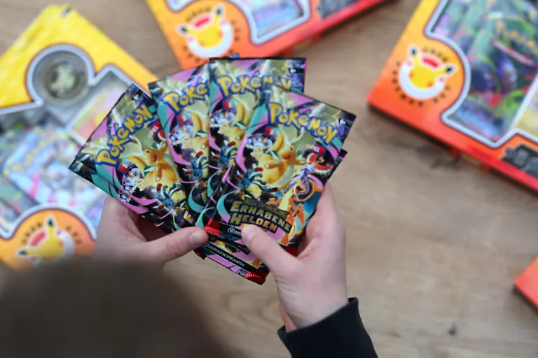 Ein-Junge-haelt-mehrere-Boosterpacks-der-neuen-Pokemon-Sammelkartenserie-Erhabene-Helden-in-den-Haenden-Die-Karten-begeistern-Sammler-und-Fans-mit-neuen-Motiven-starken-Pokemon-und-exklusiven-Designs