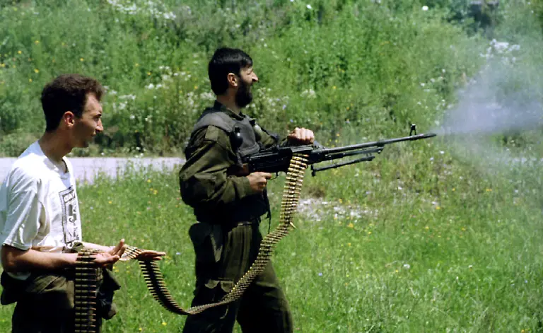 A-Bosnian-Serb-soldier-fires-a-heavy-machine-gun-as-his-comrade-holds-the-cartridge-belt-during-mopping-up-operation-near-eastern-Bosnian-town-of-Srebrenica-July-13