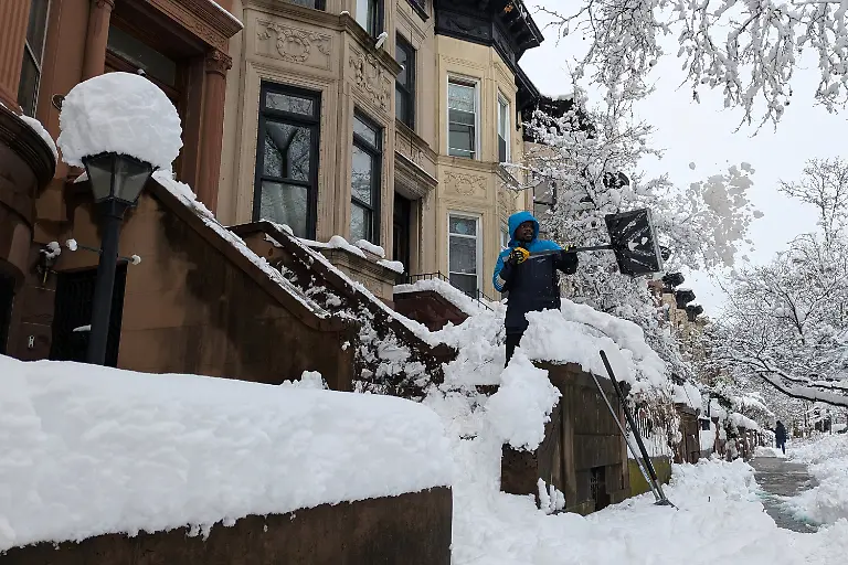 A-man-shovels-snow-from-the-front-stoop-of-a-townhouse-in-the-Brooklyn-borough-of-New-York-Monday-Feb-23-2026