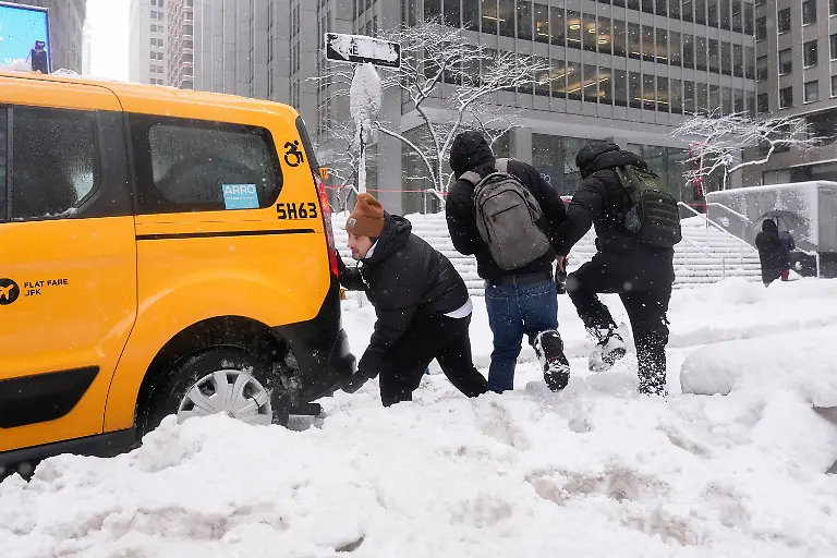 Cameron-Betz-helps-push-a-taxi-stuck-in-the-snow-during-a-snow-storm-Monday-Feb-23-2026-in-New-York
