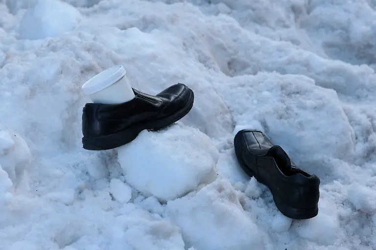 A-man-rests-his-work-shoes-and-a-soup-container-in-a-pile-of-snow-as-he-waits-for-his-bus-as-people-continue-to-deal-with-the-aftermath-of-a-major-winter-storm-that-dumped-snow-and-ice-across-a-large-swath-of-the-United-States-in-Washington-D-C-U-S-January-27-2026