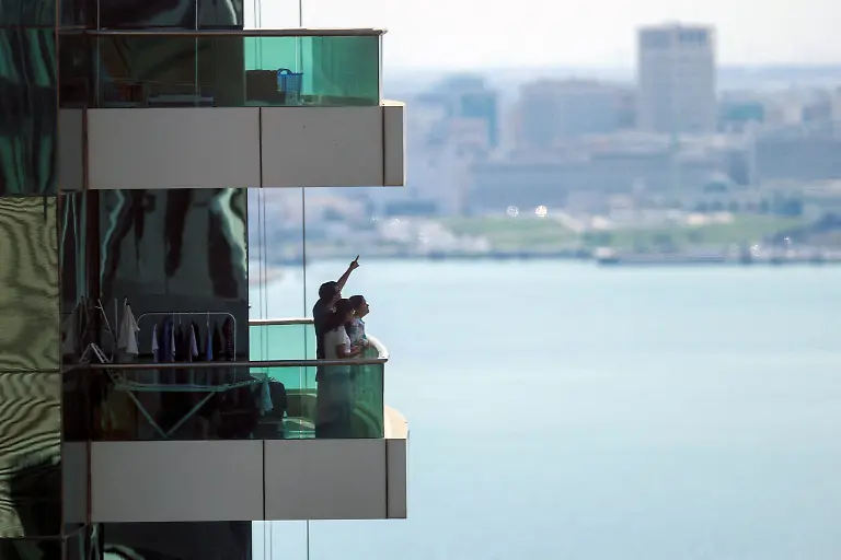 People-watch-from-their-balcony-following-explosions-after-the-Qatar-s-defense-ministry-says-it-has-downed-missiles-targeting-the-country-in-Doha-Qatar-February-28-2026