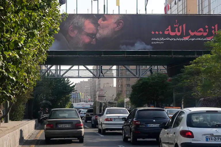 Vehicles-drive-past-a-billboard-showing-the-late-Iranian-Revolutionary-Guard-Gen-Qassem-Soleimani-who-was-killed-in-Iraq-in-a-U-S-drone-attack-in-2020-kissing-forehead-of-slain-Hezbollah-leader-Hassan-Nasrallah-in-Tehran-Iran-Saturday-Oct-5-2024