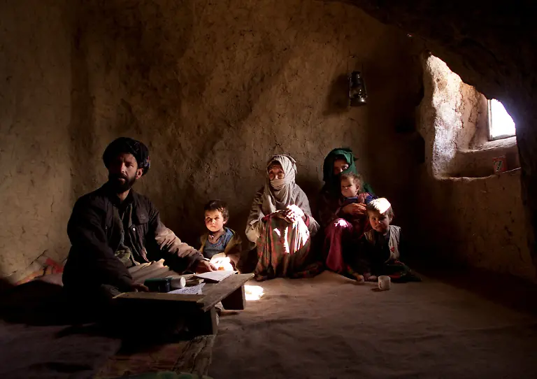 Namatullah-sits-with-his-family-members-at-their-cave-in-Bamiyan-December-15-2001-Nine-months-ago-Namatullah-s-family-fled-to-the-mountains-and-watched-from-above-as-the-Taliban-set-fire-to-their-home-in-the-village-of-Bam-Saria-Now-Namatullah-his-wife-and-three-children-again-have-a-roof-over-their-heads-but-it-is-a-cave-cut-into-the-sandstone-cliffs-where-two-giant-Buddha-statues-towered-over-the-town-of-Bamiyan-until-the-Taliban-blew-them-up-in-March