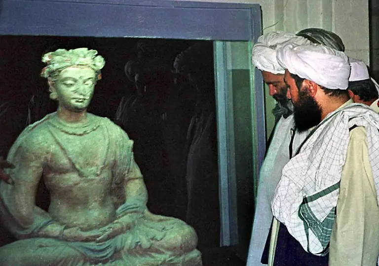Vertreter-der-in-Afghanistan-regierenden-radikal-islamischen-Taliban-Miliz-schauen-sich-am-1-8-2000-im-Museum-von-Kabul-eine-2000-Jahre-alte-und-einen-Meter-hohe-Buddha-Statue-an-Die-Taliban-Miliz-hat-am-1-3-2001-trotz-internationaler-Proteste-ihre-Drohung-wahr-gemacht-und-mit-der-Zerstoerung-alter-Statuen-begonnen-Taliban-Kulturminister-Kudratullah-Dschamal-sagte-nach-Berichten-aus-der-Hauptstadt-Kabul-Die-Arbeit-hat-begonnen-und-werde-mit-allen-Mitteln-ausgefuehrt-auch-mit-Artilleriesalven-Nach-Worten-Dschamals-begannen-Taliban-Soldaten-mit-der-Zerstoerung-von-Buesten-und-Standbildern-im-Museum-von-Kabul-und-weiterer-Kunstgegenstaende-in-den-Provinzen-Herat-Kandahar-Ningarhar-Bamiyan-und-Ghazni