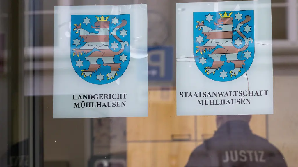Justizbeamte-stehen-zum-Prozessauftakt-vor-dem-Landgericht-Muehlhausen-Zwei-mutmassliche-Reichsbuerger-stehen-hier-heute-wegen-rund-300-Straftaten-vor-Gericht-Sie-sollen-die-Raedelsfuehrer-einer-kriminellen-Vereinigung-sein-und-ueber-Jahre-Mitarbeiter-in-Thueringer-Behoerden-mit-Droh-und-Erpressungsschreiben-ueberzogen-haben-um-sich-so-staatlichen-Zahlungsverpflichtungen-zu-entziehen-und-die-Behoerden-lahmzulegen-Darueber-hinaus-werden-einem-Angeklagten-Umsatzsteuerhinterziehungen-vorgeworfen