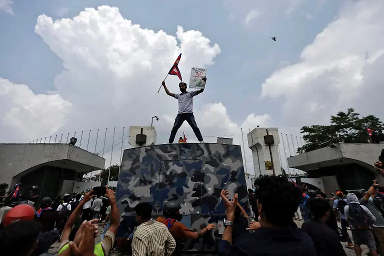 A-demonstrator-holding-a-placard-waves-Nepal-s-national-flag-as-he-stands-atop-a-water-cannon-vehicle-belonging-to-the-Armed-Police-Force-APF-outside-the-entrance-of-Parliament-during-youth-led-protests-that-toppled-Nepal-s-prime-minister-in-Kathmandu-Nepal-September-8-2025-77-people-were-killed-in-two-days-of-protests-that-later-forced-the-resignation-of-then-Prime-Minister-K-P-Sharma-Oli-and-shook-up-Nepal-s-broken-political-system-A-state-appointed-commission-charged-with-conducting-an-investigation-into-the-protests-including-the-use-of-live-ammunition-against-young-demonstrators-has-received-three-extensions-to-complete-the-probe-Its-final-findings-are-expected-to-be-released-after-the-general-election-set-for-March-5-2026-REUTERS-Navesh-Chitrakar-SEARCH-CHITRAKAR-NEPAL-PROTESTER-FAMILIES-FOR-THIS-STORY-SEARCH-WIDER-IMAGE-FOR-ALL-STORIES