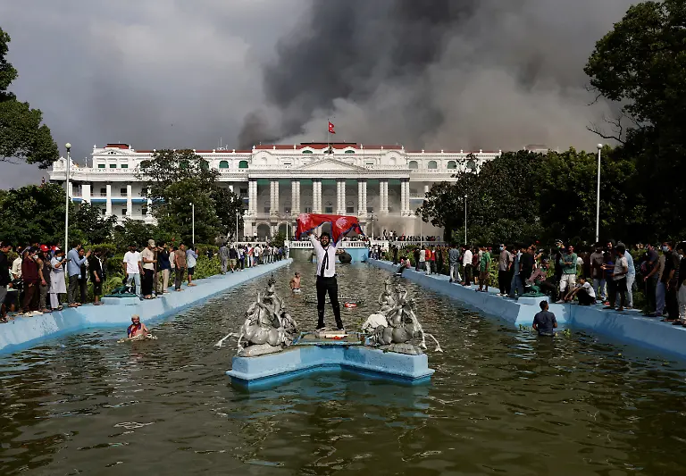 A-demonstrator-holding-Nepal-s-flag-celebrates-at-the-Singha-Durbar-office-complex-which-houses-the-prime-minister-s-office-and-other-ministries-after-storming-it-during-youth-led-protests-that-toppled-Nepal-s-prime-minister-in-Kathmandu-Nepal-September-9-2025-77-people-were-killed-in-two-days-of-protests-that-later-forced-the-resignation-of-then-Prime-Minister-K-P-Sharma-Oli-and-shook-up-Nepal-s-broken-political-system-A-state-appointed-commission-charged-with-conducting-an-investigation-into-the-protests-including-the-use-of-live-ammunition-against-young-demonstrators-has-received-three-extensions-to-complete-the-probe-Its-final-findings-are-expected-to-be-released-after-the-general-election-set-for-March-5-2026-REUTERS-Navesh-Chitrakar-SEARCH-CHITRAKAR-NEPAL-PROTESTER-FAMILIES-FOR-THIS-STORY-SEARCH-WIDER-IMAGE-FOR-ALL-STORIES