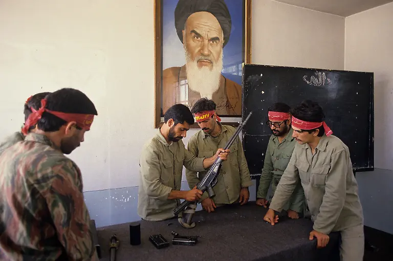 Under-watchful-eyes-of-Ayatollah-Khomeini-a-group-of-Basiji-mobilized-volunteer-forces-men-in-a-Tehran-factory-learn-to-use-fire-arms-as-part-of-mass-mobilisation-in-the-final-year-of-Iran-Iraq-war-15th-May-1988