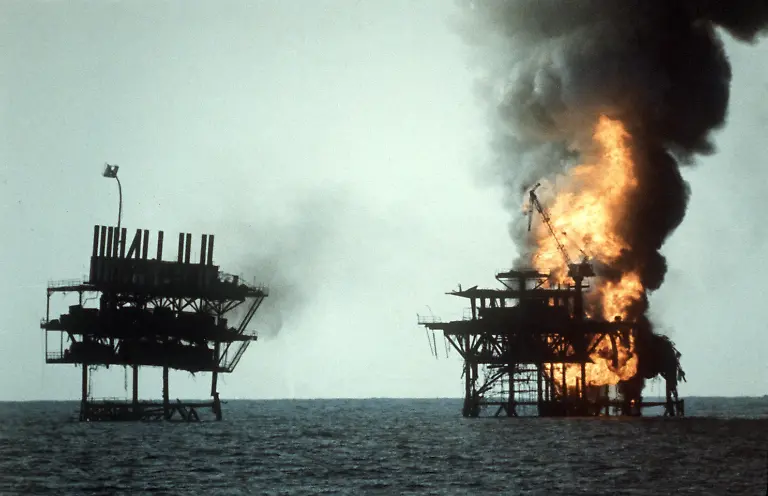 Blick-auf-die-von-den-USA-in-Brand-geschossenen-iranischen-Oelbohrplattformen-bei-Rashadat-im-Persischen-Golf-am-19-10-1987-Ein-als-begrenzte-Aktion-gedachter-Vergeltungsschlag-der-US-Streitkraefte-gegen-zwei-iranische-Oelpattformen-in-der-Nacht-zum-18-4-1988-hat-zu-den-bislang-heftigsten-Kampfhandlungen-zwischen-den-USA-und-dem-Iran-seit-der-Verstaerkung-der-US-Marinepraesenz-in-der-Region-im-vergangenen-Jahr-gefuehrt-Der-Krieg-zwischen-Iran-und-Irak-dauerte-vom-September-1980-bis-August-1988