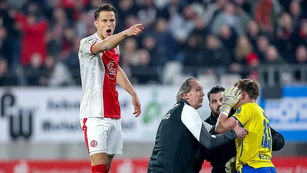 2026-03-04-Fussball-3-Liga-Herren-Rot-Weiss-Essen-SV-Waldhof-Mannheim-Stadion-Hafenstrasse-27-Spieltag-Saison-2025-2026-Torwart-Felix-Wienand-Rot-Weiss-Essen-35-kniet-verletzt-auf-dem-Spielfeld-nach-dem-Zuenden-von-Pyrotechnik-im-Gaesteblock-der-Mannheimer-Ein-Lauter-Knall-durch-einen-geworfenen-Boeller-verletzt-den-Torwart-und-fuehrt-zu-einer-Spielunterbrechung-Michael-Schultz-Rot-Weiss-Essen-04-gestikulierend-auf-dem-Spielfeld-DFB-regulations-prohibit-any-use-of-photographs-as-image-sequences-and-or-quasi-video