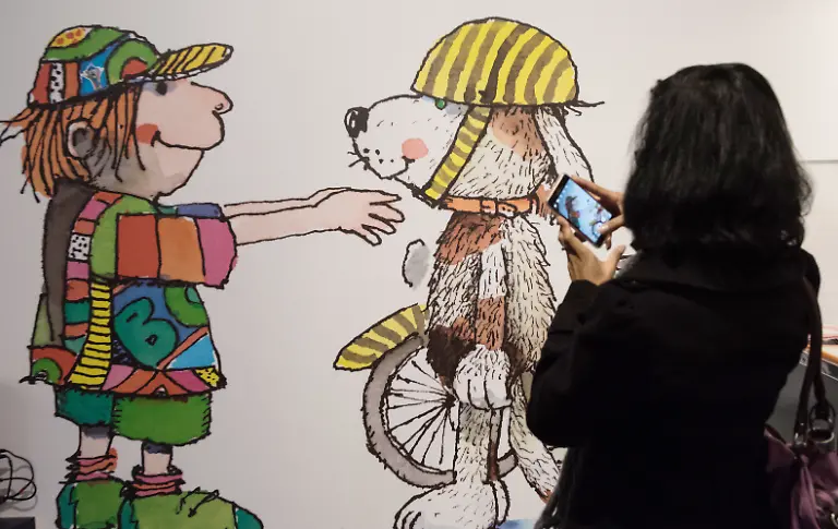 Eine-Frau-fotografiert-am-24-11-2016-im-Europa-Park-in-Rust-Baden-Wuerttemberg-ein-riesiges-Bild-des-Illustrators-Kinderbuchautors-und-Schriftstellers-Janosch-In-einer-Kunstausstellung-vom-26-11-2016-bis-08-01-2017-werden-rund-200-Werke-aus-60-Jahren-gezeigt