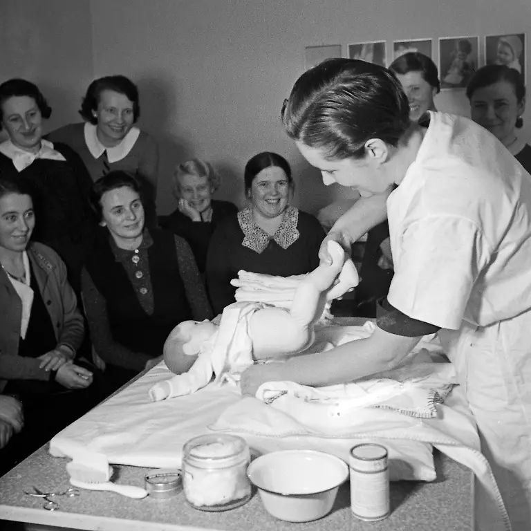 Reichsmuetterdienst-Frauen-lernen-Windelwechsel-bei-einer-Muetterschulung-des-Reichsmuetterdienstes-in-Essen-teil-Deutschland-1930er-Jahre-Women-learn-how-to-change-the-baby-s-nappy-at-a-mother-training-of-the-Reichsmuetterdienst-at-Essen-Germany-1930s
