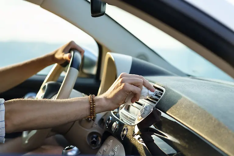 Die-Hand-des-Fahrers-wischt-Staub-von-der-Lueftungsoeffnung-des-Armaturenbretts-um-die-Funktion-der-Belueftungsanlage-zu-verbessern-Man-takes-care-of-work-of-air-ventilation-system-when-driving-car-sitting-at-driver-seat-and-controlling-steering-wheel-Hand-of-driver-wipes-dust-from-panel-vent-for-air-flow-during-road-trip-closeup-LicenseRF-Copyright-xZoonar