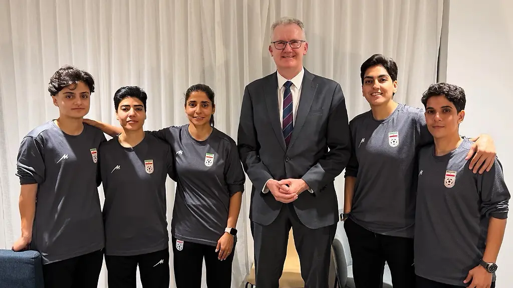 Auf-diesem-Foto-das-vom-Buero-des-australischen-Innenministers-Burke-zur-Verfuegung-gestellt-wurde-posiert-der-Minister-Tony-Burke-M-an-einem-ungenannten-Ort-mit-fuenf-Spielerinnen-der-iranischen-Frauenfussball-Nationalmannschaft-die-in-Australien-Asyl-erhalten-haben