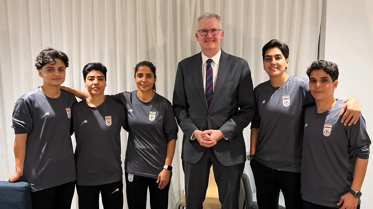 Auf-diesem-Foto-das-vom-Buero-des-australischen-Innenministers-Burke-zur-Verfuegung-gestellt-wurde-posiert-der-Minister-Tony-Burke-M-an-einem-ungenannten-Ort-mit-fuenf-Spielerinnen-der-iranischen-Frauenfussball-Nationalmannschaft-die-in-Australien-Asyl-erhalten-haben
