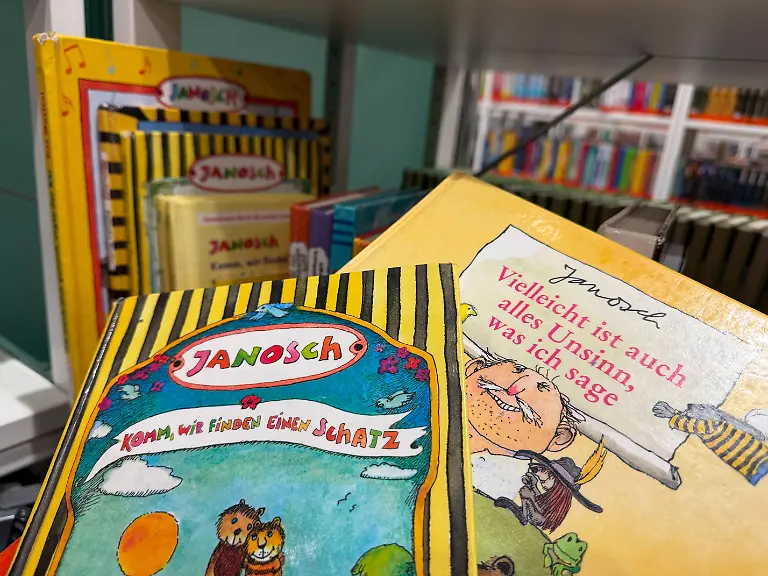 Buecher-des-deutschen-Illustrators-Kinderbuchautors-und-Schriftstellers-Janosch-buergerlich-Horst-Eckert-in-einer-Buecherei-in-Frankfurt-Foto-vom-05-03-2026-Seine-liebevoll-gezeichneten-Figuren-leben-in-einer-heilen-Welt-der-Freundschaft-und-Fantasie-seine-eigene-Kindheit-hingegen-war-gepraegt-von-Furcht-und-Pruegeln-Am-11-Maerz-wird-Kinderbuchautor-Janosch-95-Jahre-alt-Sein-Lebenswerk-ist-riesig-Er-hat-mehr-als-150-Buecher-geschrieben-und-illustriert-sie-wurden-in-ueber-30-Sprachen-uebersetzt-1980-zog-er-sich-auf-die-Kanaren-Insel-Teneriffa-zurueck-Siehe-epd-Feature-vom-09-03