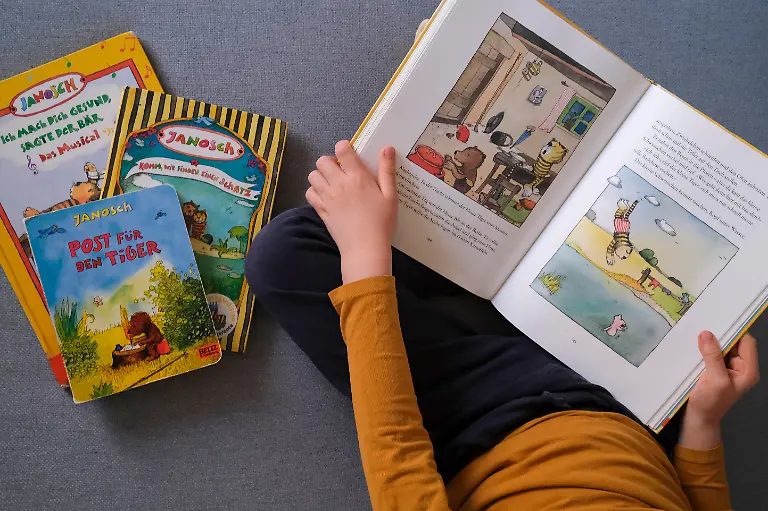 Ein-Kind-guckt-sich-Buecher-des-deutschen-Illustrators-Kinderbuchautors-und-Schriftstellers-Janosch-buergerlich-Horst-Eckert-an-Symbolfoto-vom-08-03-2026-Seine-liebevoll-gezeichneten-Figuren-leben-in-einer-heilen-Welt-der-Freundschaft-und-Fantasie-seine-eigene-Kindheit-hingegen-war-gepraegt-von-Furcht-und-Pruegeln-Am-11-Maerz-wird-Kinderbuchautor-Janosch-95-Jahre-alt-Sein-Lebenswerk-ist-riesig-Er-hat-mehr-als-150-Buecher-geschrieben-und-illustriert-sie-wurden-in-ueber-30-Sprachen-uebersetzt-1980-zog-er-sich-auf-die-Kanaren-Insel-Teneriffa-zurueck-Siehe-epd-Feature-vom-09-03