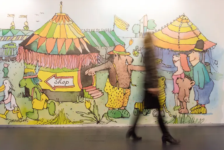 Eine-Frau-geht-am-24-11-2016-im-Europa-Park-in-Rust-Baden-Wuerttemberg-vor-einem-riesigen-Bild-des-Illustrators-Kinderbuchautors-und-Schriftstellers-Janosch-entlang-In-einer-Kunstausstellung-vom-26-11-2016-bis-08-01-2017-werden-rund-200-Werke-aus-60-Jahren-gezeigt