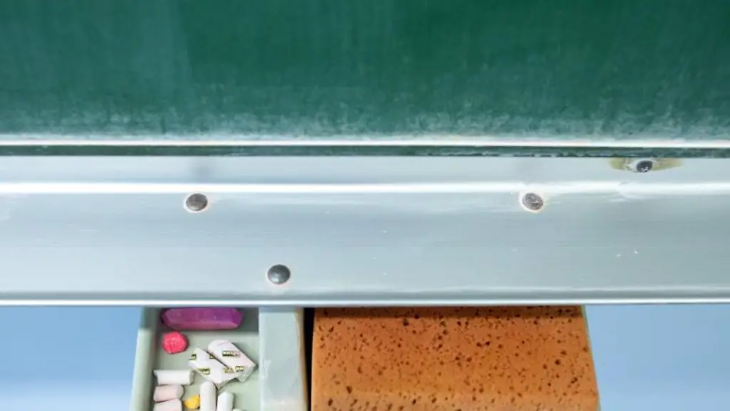 Schwamm-und-Kreide-liegen-in-einem-Klassenraum-unter-einer-Tafel