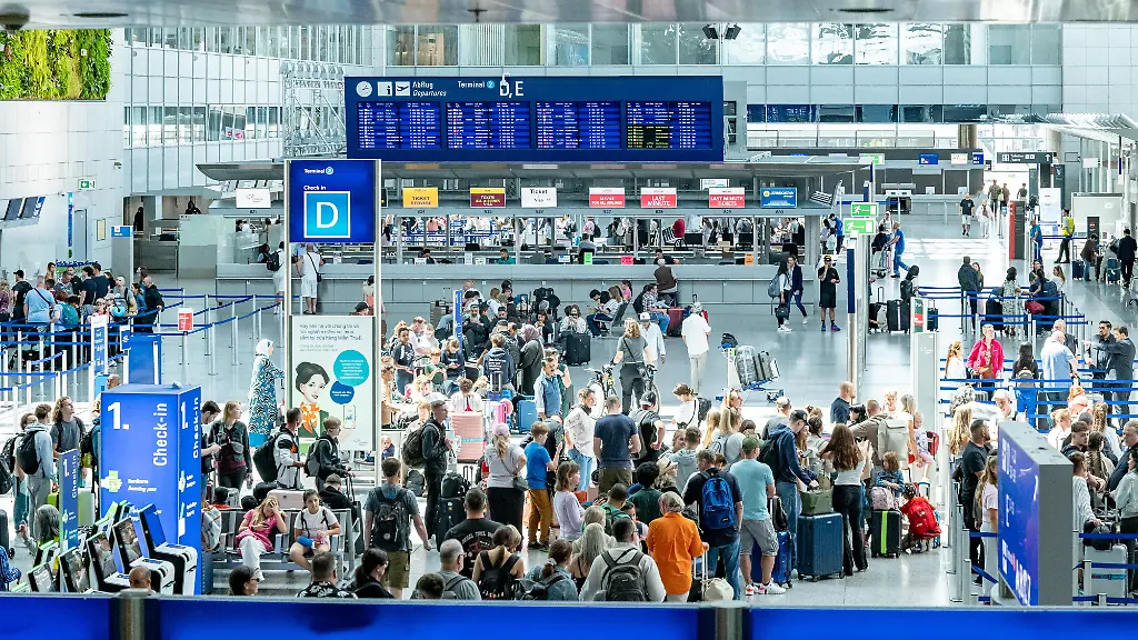 22-07-25-Frankfurt-Symbolfoto-Illustrationsbild-Symbolbild-Illustrationsfoto-Alltagsszene-Weitwinkelaufnahme-vom-Check-in-Bereich-im-Terminal-D-des-Frankfurter-Flughafens-Hunderte-Menschen-warten-in-Schlangen-an-den-Schaltern-Ueber-den-Koepfen-ist-eine-grosse-digitale-Abflugtafel-zu-sehen-die-internationale-Flugverbindungen-anzeigt-Die-Szene-dokumentiert-eindrucksvoll-das-hohe-Passagieraufkommen-in-Spitzenzeiten-und-den-logistischen-Ablauf-im-Luftverkehr