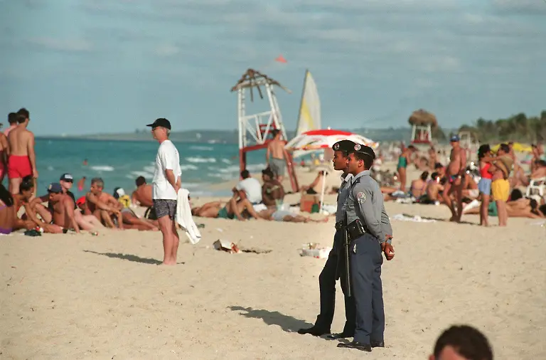 Zwei-Polizisten-bewachen-den-Strand-von-Guanabo-der-ein-beliebtes-Ziel-von-Touristen-ist-aufgenommen-1997-Alle-Straende-in-Kuba-an-denen-sich-Touristen-aufhalten-werden-von-der-kubanischen-Polizei-bewacht-Aufgenommen-1997-In-der-kubanischen-Wirtschaft-steht-offenbar-ein-Wandel-bevor-Seit-1990-waechst-der-Fremdenverkehr-in-Havanna-nach-Angaben-des-stellvertretenden-Tourismusministers-Miguel-Brugueras-jaehrlich-um-durchschnittlich-17-Prozent-Angesichts-dieser-positiven-Entwicklung-will-die-Regierung-weiter-auf-den-Tourismus-setzen-und-entsprechend-die-Infrastruktur-ausbauen-Derzeit-gibt-es-rund-24000-Hotelzimmer-Bis-zum-Jahre-2000-sollen-es-schon-50000-sein