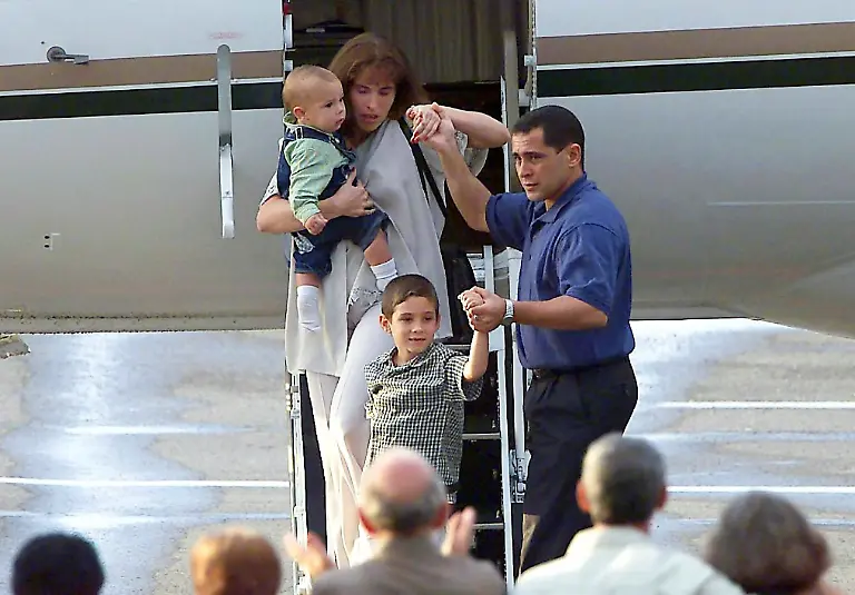 Der-sechsjaehrige-Fluechtlingsjunge-Elian-Gonzalez-trifft-mit-seinem-Vater-Juan-Miguel-Gonzalez-seiner-Stiefmutter-Nersy-Carmenate-und-seinem-Stiefbruder-Hianny-am-28-6-2000-auf-dem-Flughafen-in-Havanna-ein-Nach-sieben-Monaten-ist-der-Fluechtlingsjunge-Elian-aus-den-USA-nach-Kuba-abgeflogen-Damit-ist-ein-siebenmonatiger-erbitterter-Sorgerechtsstreit-zu-Ende-Sein-Vater-dankte-auf-dem-Washingtoner-Flughafen-den-USA-fuer-ihre-Unterstuetzung-Wenige-Stunden-zuvor-hatte-das-Oberste-Gericht-der-USA-einen-letzten-Einspruch-von-Elians-Verwandten-in-Florida-verworfen-Praesident-Bill-Clinton-begruesste-die-Entscheidung-der-Richter-Die-exil-kubanische-Gemeinde-in-den-USA-reagierte-dagegen-geschockt