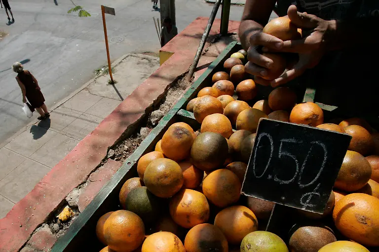 TO-GO-WITH-STORY-SLUGGED-CUBA-LIVING-ON-THE-LIBRETA-A-woman-leaves-a-local-market-as-a-man-top-right-sells-oranges-in-Havana-Sunday-May-6-2007-The-ration-book-that-determines-most-Cuban-s-diets-list-types-and-amounts-of-foodstuffs-to-be-checked-signed-and-stamped-at-the-local-government-food-distribution-center-Cuba-s-universal-ration-program-was-launched-in-1962-to-guarantee-citizens-a-basic-amount-of-food-at-low-prices