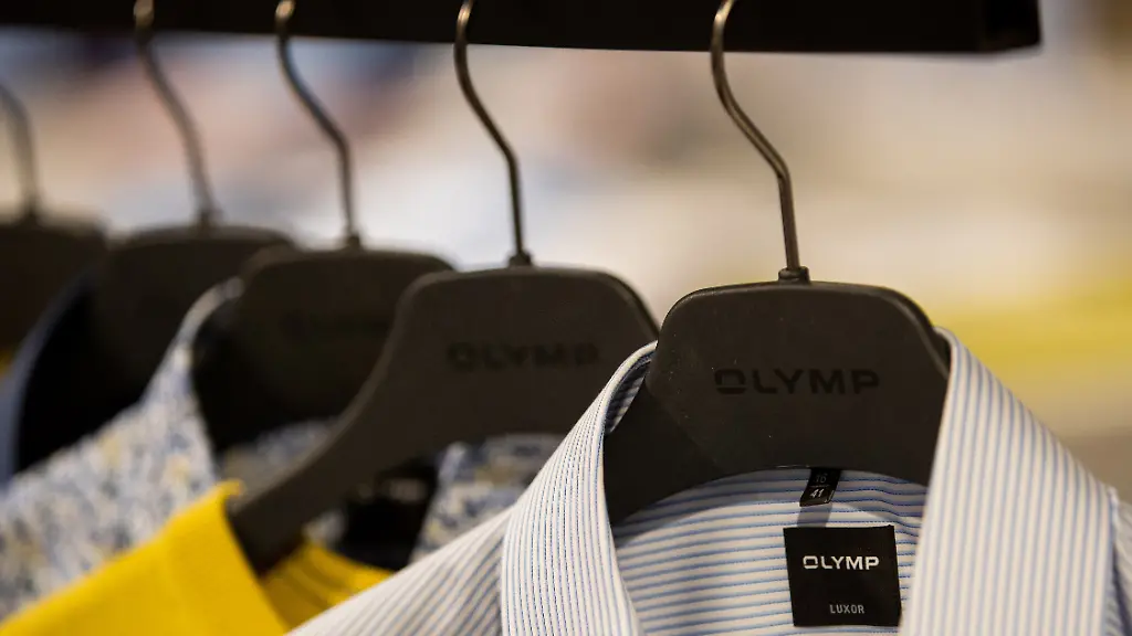 Das-Logo-von-Olymp-ist-in-einem-Hemd-und-an-einem-Kleiderbuegel-zu-sehen