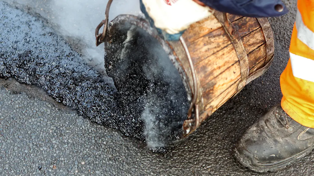 Ein-Asphaltierer-vom-Tief-und-Hafenbauamt-flickt-am-Dienstag-11-01-2011-in-Rostock-ein-Schlagloch-Der-strenge-Winter-der-vergangenen-Wochen-hat-grosse-Schaeden-hinterlassen-Vor-allem-aeltere-Strassen-sind-betroffen