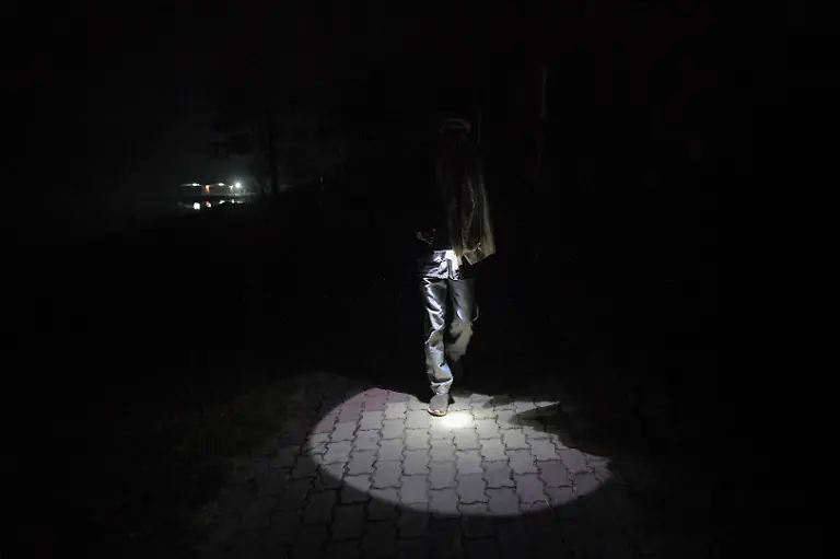 Security-guard-Pannelal-Rajak-78-flashes-his-torch-as-he-checks-the-premises-of-the-tourism-site-during-his-night-shift-at-Kenapara-Eco-Park-which-was-developed-from-a-closed-open-cast-coal-mine-pit-into-a-small-tourist-hub-in-Surajpur-India-November-16-2025-Decades-ago-Rajak-gave-up-his-land-for-the-Bishrampur-open-cast-coal-mine-in-exchange-for-money-and-a-job-in-the-mine-he-believed-would-follow-but-he-never-got-the-job-Today-he-guards-the-same-mine-At-least-I-am-earning-something-here-now-he-says-REUTERS-Avijit-Ghosh-SEARCH-INDIA-GHOSH-COAL-FOR-THIS-STORY-SEARCH-WIDER-IMAGE-FOR-ALL-STORIES