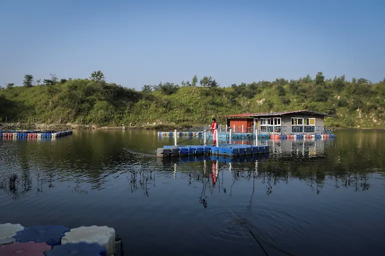 Savita-Gupta-28-moves-a-makeshift-boat-made-of-floating-pontoons-towards-land-using-a-rope-at-Kenapara-Eco-Park-which-was-developed-from-a-closed-open-cast-coal-mine-pit-into-a-small-tourist-hub-in-Surajpur-India-November-17-2025-The-site-which-began-to-be-repurposed-for-tourism-in-2018-is-managed-by-a-women-s-community-group-and-a-fishery-cooperative-and-attracts-as-many-as-150-people-at-the-weekend-and-for-the-women-the-gains-have-gone-beyond-income-I-hope-my-daughter-will-learn-from-my-life-and-think-about-becoming-an-independent-woman-Gupta-said-REUTERS-Avijit-Ghosh-SEARCH-INDIA-GHOSH-COAL-FOR-THIS-STORY-SEARCH-WIDER-IMAGE-FOR-ALL-STORIES