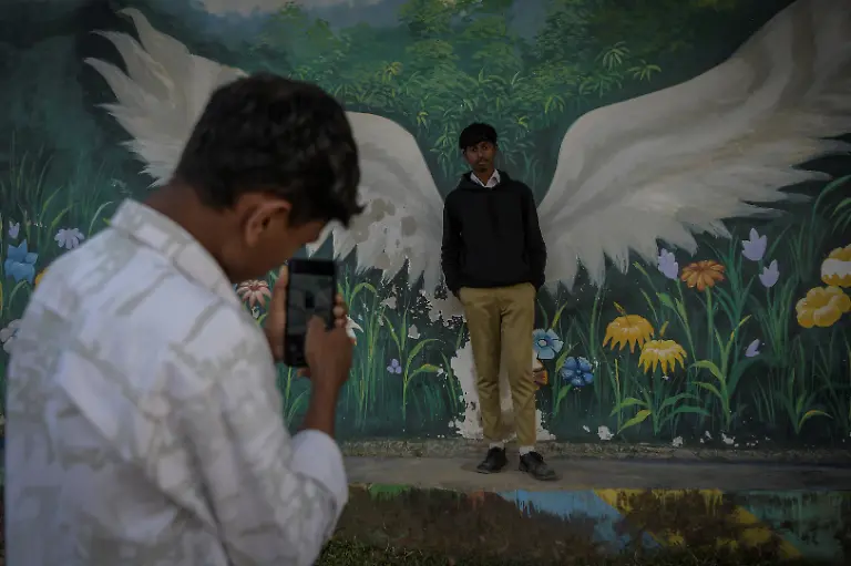 Matadeen-19-poses-for-a-photo-in-front-of-graffiti-as-his-friend-takes-his-picture-on-a-phone-at-Kenapara-Eco-Park-which-was-developed-from-a-closed-open-cast-coal-mine-pit-into-a-small-tourist-hub-in-Surajpur-India-November-14-2025-The-site-which-began-to-be-repurposed-for-tourism-in-2018-is-managed-by-a-women-s-community-group-and-a-fishery-cooperative-and-attracts-as-many-as-150-people-at-the-weekend-REUTERS-Avijit-Ghosh-SEARCH-INDIA-GHOSH-COAL-FOR-THIS-STORY-SEARCH-WIDER-IMAGE-FOR-ALL-STORIES