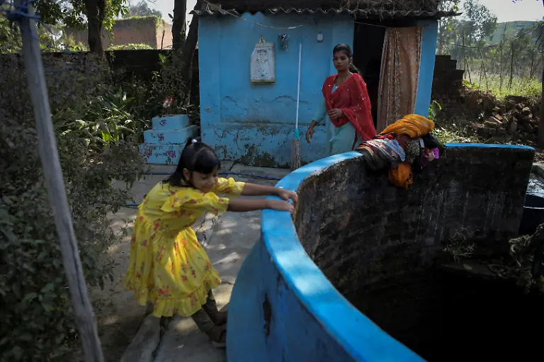 Bhumi-Gupta-9-plays-as-her-mother-Savita-Gupta-28-who-is-part-of-a-self-help-group-that-runs-a-floating-restaurant-at-Kenapara-Eco-Park-walks-past-their-house-in-Surajpur-India-November-16-2025-The-site-which-began-to-be-repurposed-for-tourism-in-2018-is-managed-by-a-women-s-community-group-and-a-fishery-cooperative-and-attracts-as-many-as-150-people-at-the-weekend-and-for-the-women-the-gains-have-gone-beyond-income-I-hope-my-daughter-will-learn-from-my-life-and-think-about-becoming-an-independent-woman-Gupta-said-REUTERS-Avijit-Ghosh-SEARCH-INDIA-GHOSH-COAL-FOR-THIS-STORY-SEARCH-WIDER-IMAGE-FOR-ALL-STORIES