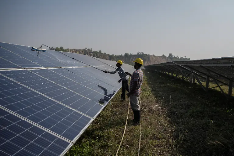 Workers-clean-installed-solar-panels-at-a-12MW-solar-PV-power-plant-set-up-as-part-of-the-land-reclamation-plan-for-the-Bishrampur-OC-coal-mining-area-in-Surajpur-India-November-16-2025-A-40-hectare-solar-park-generating-12-megawatts-of-power-employs-several-local-residents-and-officials-say-they-have-restored-several-hundred-hectares-of-former-mining-land-planting-trees-including-sheesham-a-North-Indian-rosewood-and-mango-SECL-has-spent-around-43-million-rupees-developing-the-project-government-data-shows-REUTERS-Avijit-Ghosh-SEARCH-INDIA-GHOSH-COAL-FOR-THIS-STORY-SEARCH-WIDER-IMAGE-FOR-ALL-STORIES