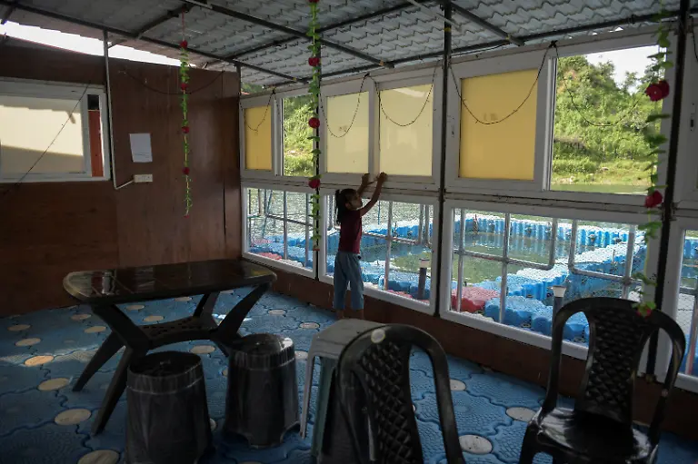 Bhumi-Gupta-9-daughter-of-Savita-Gupta-28-opens-a-window-of-the-floating-restaurant-run-by-a-self-help-group-that-her-mother-is-part-of-at-Kenapara-Eco-Park-which-was-developed-from-a-closed-open-cast-coal-mine-pit-into-a-small-tourist-hub-in-Surajpur-India-August-10-2025-The-site-which-began-to-be-repurposed-for-tourism-in-2018-is-managed-by-a-women-s-community-group-and-a-fishery-cooperative-and-attracts-as-many-as-150-people-at-the-weekend-and-for-the-women-the-gains-have-gone-beyond-income-I-hope-my-daughter-will-learn-from-my-life-and-think-about-becoming-an-independent-woman-Gupta-said-REUTERS-Avijit-Ghosh-SEARCH-INDIA-GHOSH-COAL-FOR-THIS-STORY-SEARCH-WIDER-IMAGE-FOR-ALL-STORIES