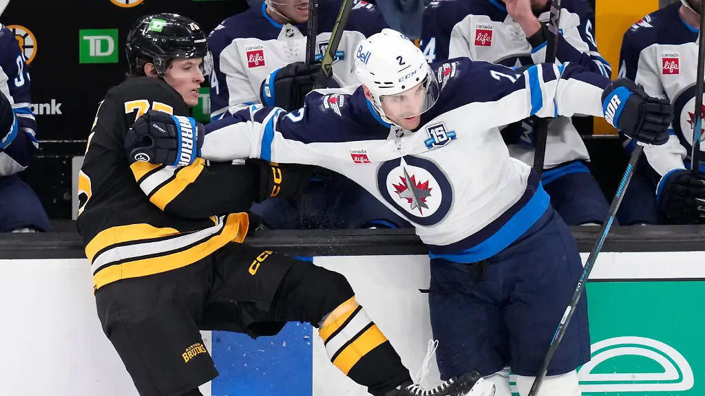 Boston-Bruins-left-wing-Lukas-Reichel-left-is-held-back-by-Winnipeg-Jets-defenseman-Dylan-DeMelo-during-the-first-period-of-an-NHL-hockey-game-Thursday-March-19-2026-in-Boston