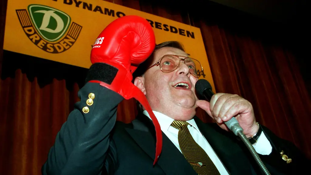 Rote-Boxhandschuhe-waren-das-Geschenk-fuer-Rolf-Juergen-Otto-nach-der-Wiederwahl-als-Praesident-beim-Fussball-Bundesligisten-1-FC-Dynamo-Dresden-auf-der-Jahreshauptversammlung-am-27-10-94-in-der-saechsischen-Landeshauptstadt-Mit-einem-an-DDR-Wahlen-erinnernden-Ergebnis-nur-eine-Gegenstimme-und-zehn-Enthaltungen-bei-287-anwesenden-Mitgliedern-wurde-der-54jaehrige-Bauunternehmer-in-der-ehemaligen-SED-Bezirksparteischule-als-einziger-Kandidat-fuer-die-naechsten-zwei-Jahre-in-seinem-Amt-bestaetigt-Otto-hatte-den-einzigen-Erstligisten-aus-den-neuen-Bundeslaendern-bereits-seit-dem-23-Januar-1993-gefuehrt-und-den-Schuldenberg-nach-und-nach-auf-nur-noch-9-2-Millionen-Mark-abgebaut