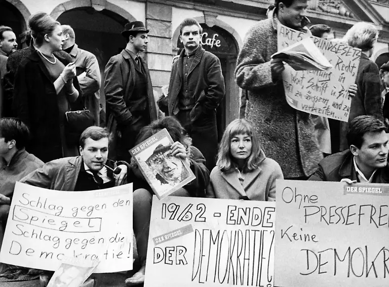 Gegen-die-Verhaftung-von-Spiegel-Redakteuren-demonstriert-am-30-10-1962-eine-Gruppe-von-Studenten-vor-der-Frankfurter-Hauptwache-mit-einem-Sitzstreik-Der-am-8-10-1962-im-Spiegel-veroeffentlichte-Artikel-Bedingt-abwehrbereit-von-Conrad-Ahlers-fuehrte-zur-Durchsuchung-der-Verlagsraeume-der-Spiegel-Redaktionen-in-Hamburg-und-Bonn-und-zur-Verhaftung-mehrerer-Personen-unter-anderem-Herausgeber-Rudolf-Augstein-und-Chefredakteur-Claus-Jacobi-wegen-Landesverrats-Die-Anschuldigungen-erwiesen-sich-als-haltlos-Bundesverteidigungsminister-Franz-Josef-Strauss-verlor-sein-Amt-Die-Spiegelaffaere-im-Herbst-1962-war-die-erste-groessere-innenpolitische-Krise-der-Bundesrepublik-Deutschland