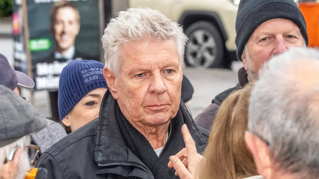 OB-Dieter-Reiter-SPD-bei-Wahlkampftermin-im-Gespraech-mit-Buergern-er-tritt-in-der-Stichwahl-gegen-Dominik-Krause-von-den-Gruenen-an-dessen-Wahlplakat-im-Hintergrund-zu-sehen-ist-Muenchen-17-Maerz-2026-Deutschland-Muenchen-17-Maerz-2026-Dieter-Reiter-SPD-bei-Wahlkampftermin-umringt-von-Buergern-Reiter-ist-Muenchner-Obuergermeister-steht-jetzt-in-der-Stichwahl-gegen-Dominik-Krause-Die-Gruenen-der-ihm-auf-dem-Wahlplakat-hinten-ueber-die-Schulter-schaut-OB-Reiter-am-Dienstagmorgen-ab-9-30-Uhr-am-Busbahnhof-Kieferngarten-im-Gespraech-mit-Passanten-Wahlkampfveranstaltung-Muenchner-Kommunalwahlkampf-Stichwahl-am-22