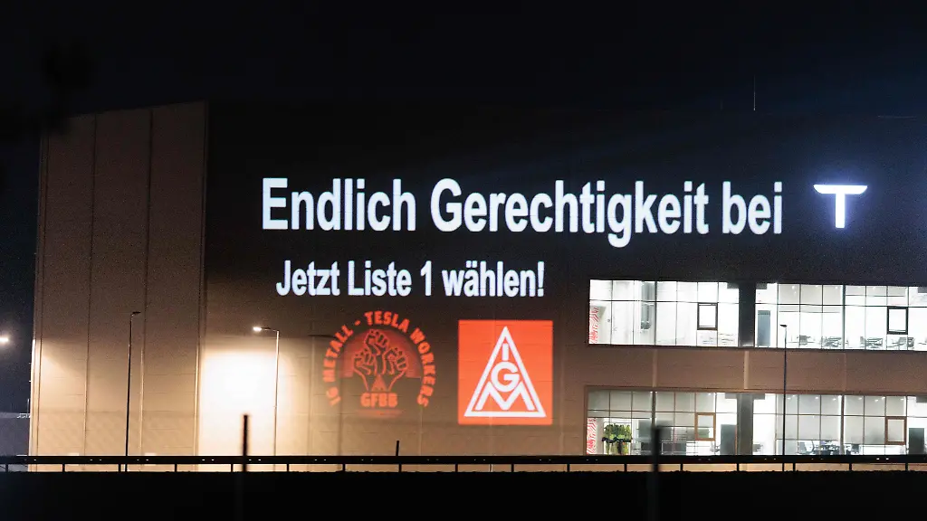 Mitglieder-der-IG-Metall-beleuchten-bei-einer-Protestaktion-mit-dem-Slogan-Endlich-Gerechtigkeit-bei-T-Jetzt-Liste-1-waehlen-die-Zellfabrik-auf-dem-Werksgelaende-des-Autobauers-Tesla-vor-den-bevorstehenden-Betriebsratswahlen