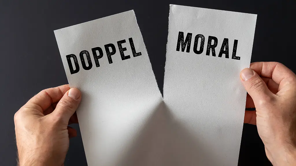 Bavaria-Germany-November-10-2025-PHOTOMONTAGE-Two-hands-holding-a-torn-sheet-of-paper-with-the-word-double-standards-Symbolic-image-hypocrisy-contradictory-behavior-and-moral-contradictions-FOTOMONTAGE-Zwei-Haende-halten-ein-zerrissenes-Blatt-Papier-mit-dem-Wort-Doppelmoral