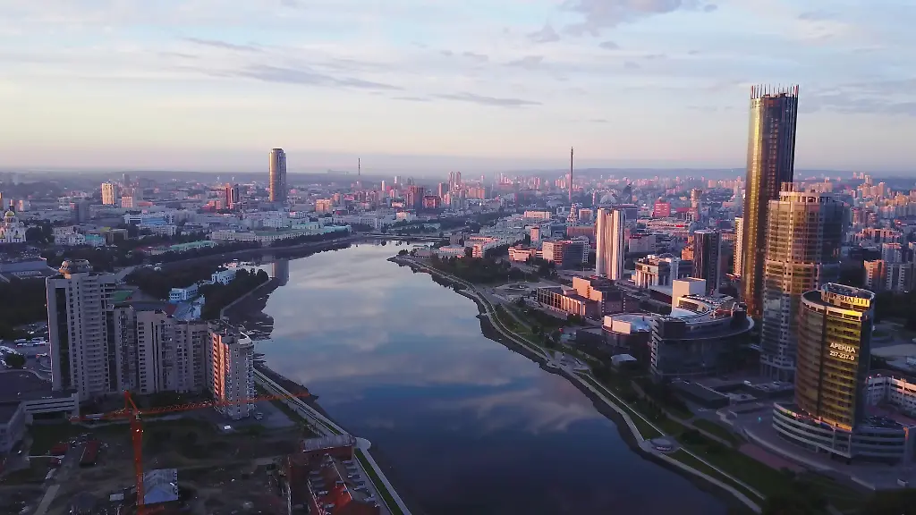 Wunderschoenes-Panorama-einer-modernen-Stadt-mit-Spiegelung-des-Himmels-im-Fluss-bei-Sonnenuntergang-Archivmaterial-Die-moderne-Stadt-wurde-von-der-untergehenden-Sonne-in-Rosa-getaucht-Hochhaeuser-spiegeln-die-untergehende-Sonne-vor-dem-Hintergrund-der-r-Beautiful-panorama-of-modern-city-with-reflection-of-sky-in-river-at-sunset-Stock-footage-Modern-city-was-painted-pink-by-setting-sun-High-rises-reflect-setting-sun-on-background-of-pink-city-LicenseRF-Copyright-xZoonar