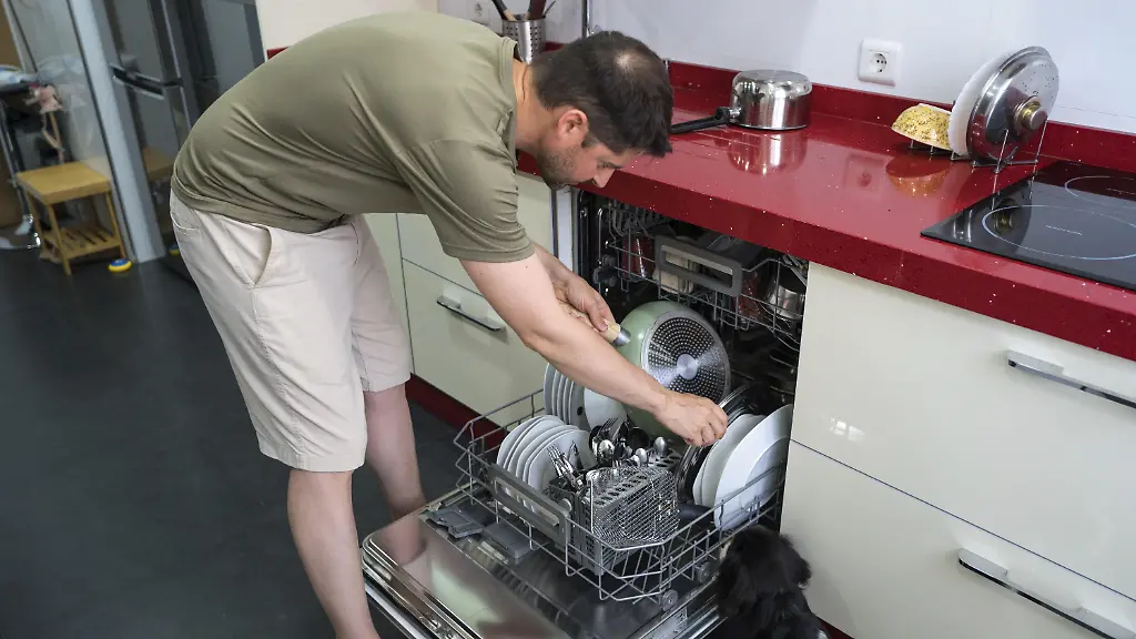 Ein-Mann-in-Freizeitkleidung-laedt-Geschirr-in-eine-Spuelmaschine-in-einer-modernen-Kueche