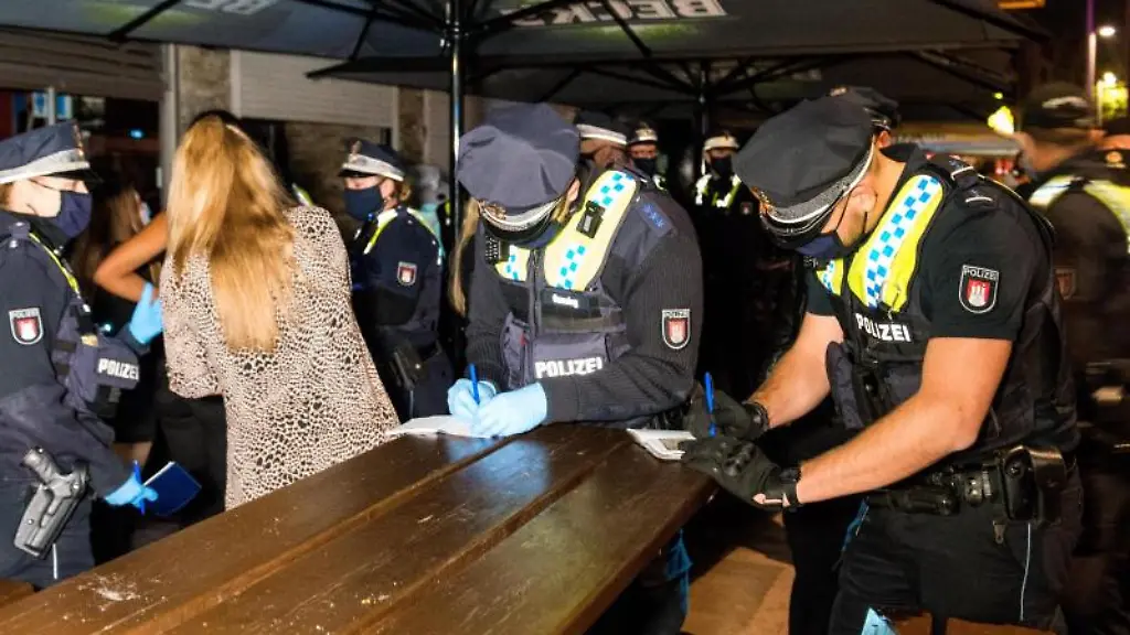 Polizisten-nehmen-vor-einer-Discothek-auf-der-Reeperbahn-die-Personalien-von-Besuchern-auf-die-sich-trotz-der-Sperrstunde-verbotenerweise-in-dem-Club-aufgehalten-und-spaeter-versteckt-haben