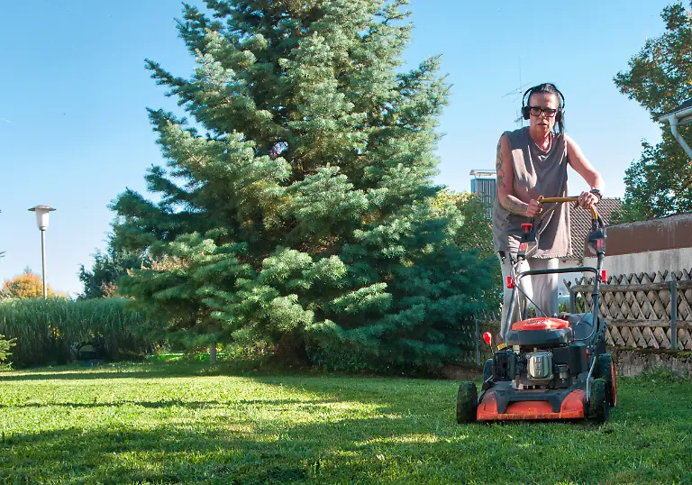 Eine-Person-maeht-an-einem-sonnigen-Herbsttag-mit-einem-Benzin-Rasenmaeher-den-Rasen-in-einem-privaten-Garten