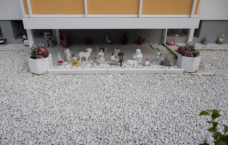 Plastikblumen-dekoriert-ist-dieser-Schottergarten-an-einem-Wohnhaus-in-Hanau-Schotter-oder-Kiesgaerten-gelten-zwar-als-pflegeleicht-werden-aber-unter-Klimaschutzaspekten-kontrovers-diskutiert