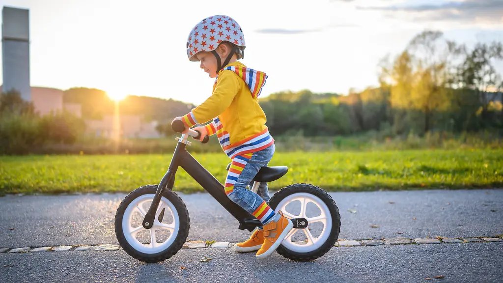 Caucasian-boy-with-sports-helmets-driving-balance-bike-outdoors-on-a-sunny-day-He-is-learning-new-skill