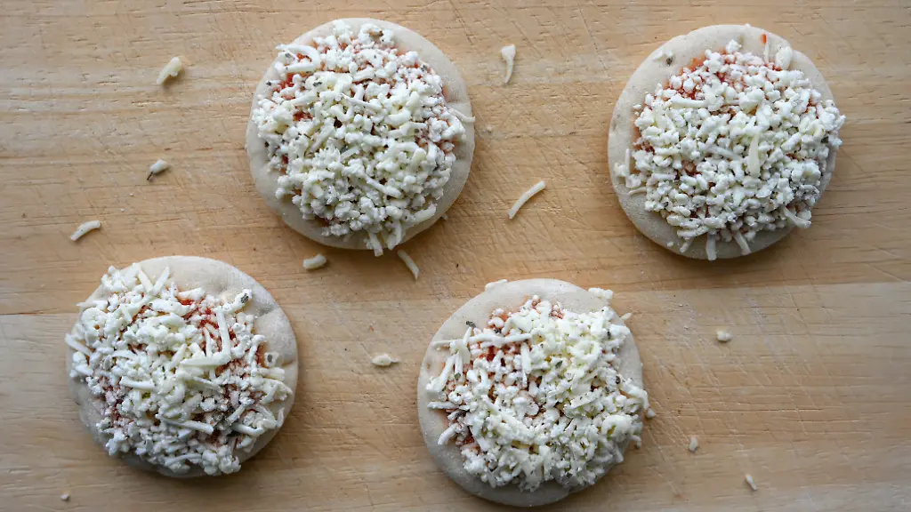Tiefgekuehlte-Mini-Pizza-Margherita-auf-einem-Kuechenbrett