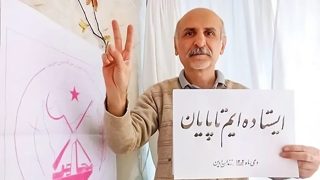 Karaj-Iran-30-03-2026-Mohammad-Taghavi-makes-a-victory-sign-while-holding-a-Persian-sign-reading-Execution-is-the-regimes-crime-in-a-portrait-image-in-Evin-Prison-on-Jan-2023-The-image-refers-to-his-execution-along-with-Akbar-Shahrokh-Daneshvarkar-on-March-30-2026-at-Ghezel-Hesar-Prison-in-Karaj-Both-were-members-of-the-Peoples-Mojahedin-Organization-of-Iran-PMOI-MEK-and-were-sentenced-to-death-by-Tehrans-Revolutionary-Court